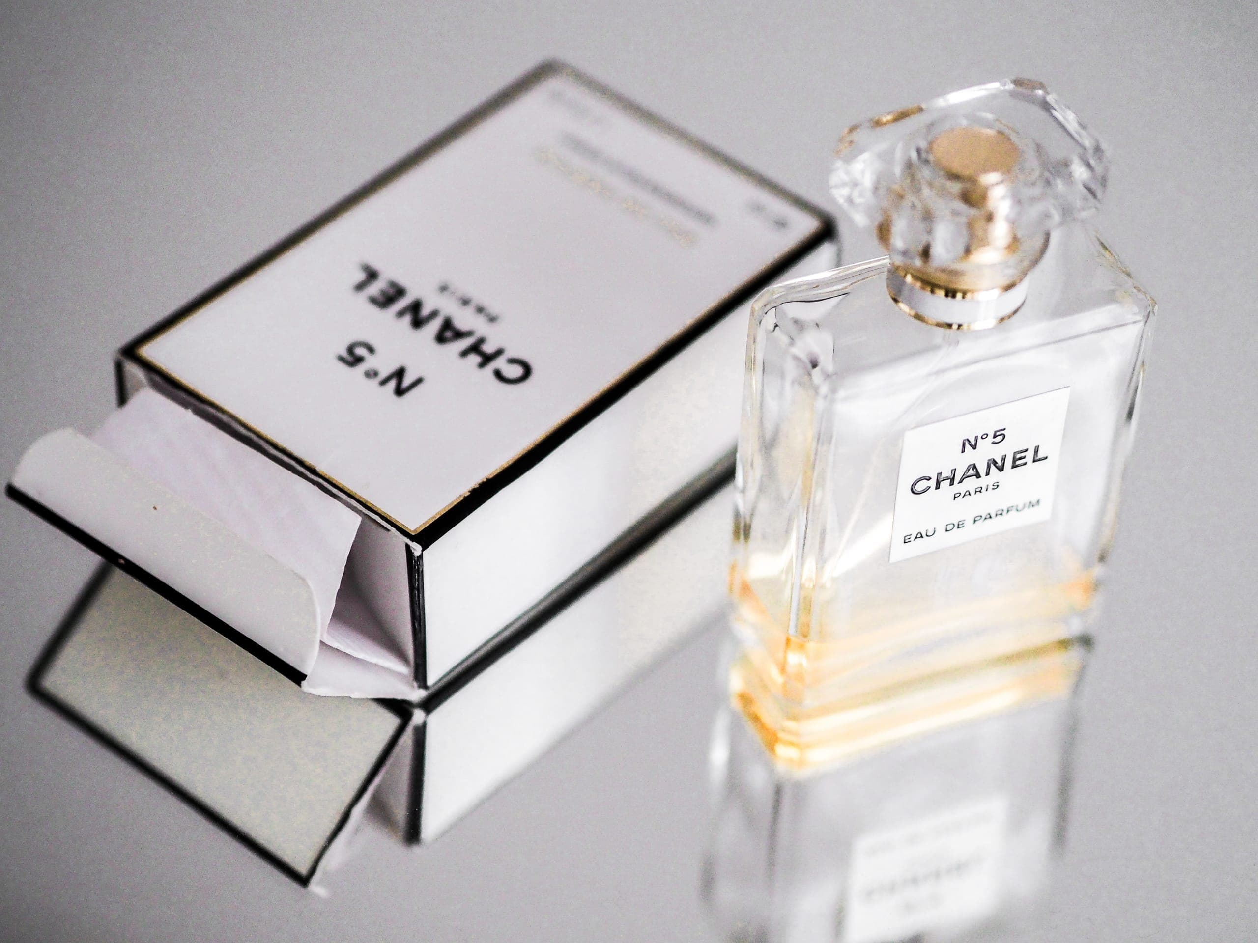 A luxury perfume bottle and its packaging on a mirrored surface