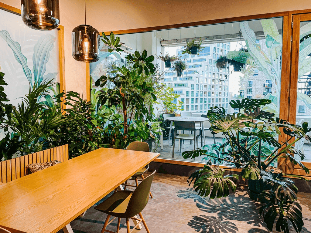 Groene overleghoek met houten tafel en planten op het kantoor van Codemaker-S