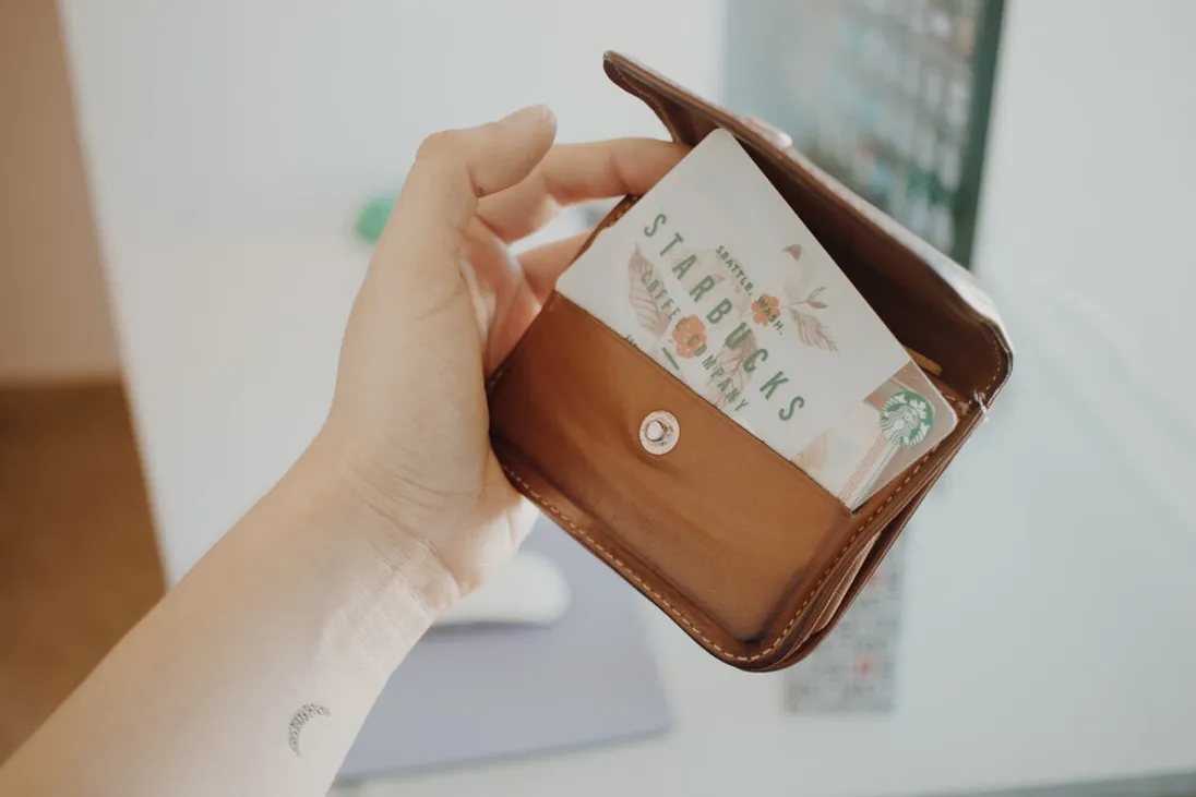 Hand houdt een portemonnee vast met daarin een Starbucks-loyaliteitskaart